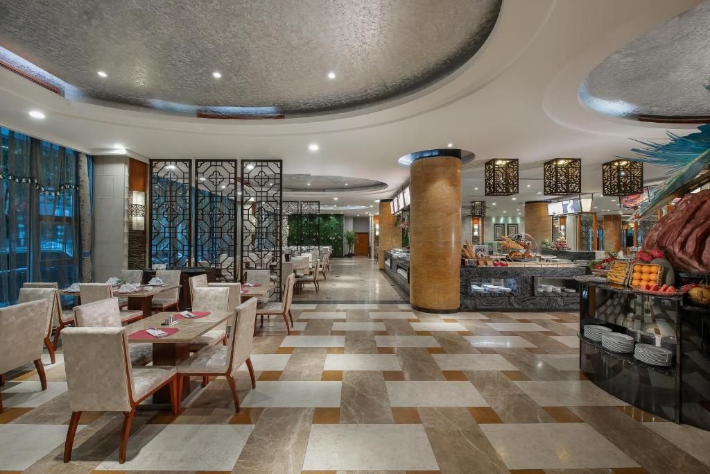 A hotel lobby with a checkered floor, seating areas, a buffet, and decorative panels.