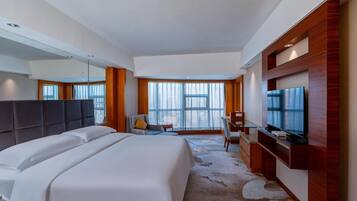 Una habitación de hotel con una cama grande, televisión, escritorio y silla.