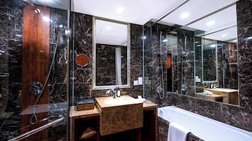 A modern bathroom with a marble shower, a wooden vanity, and a large mirror.