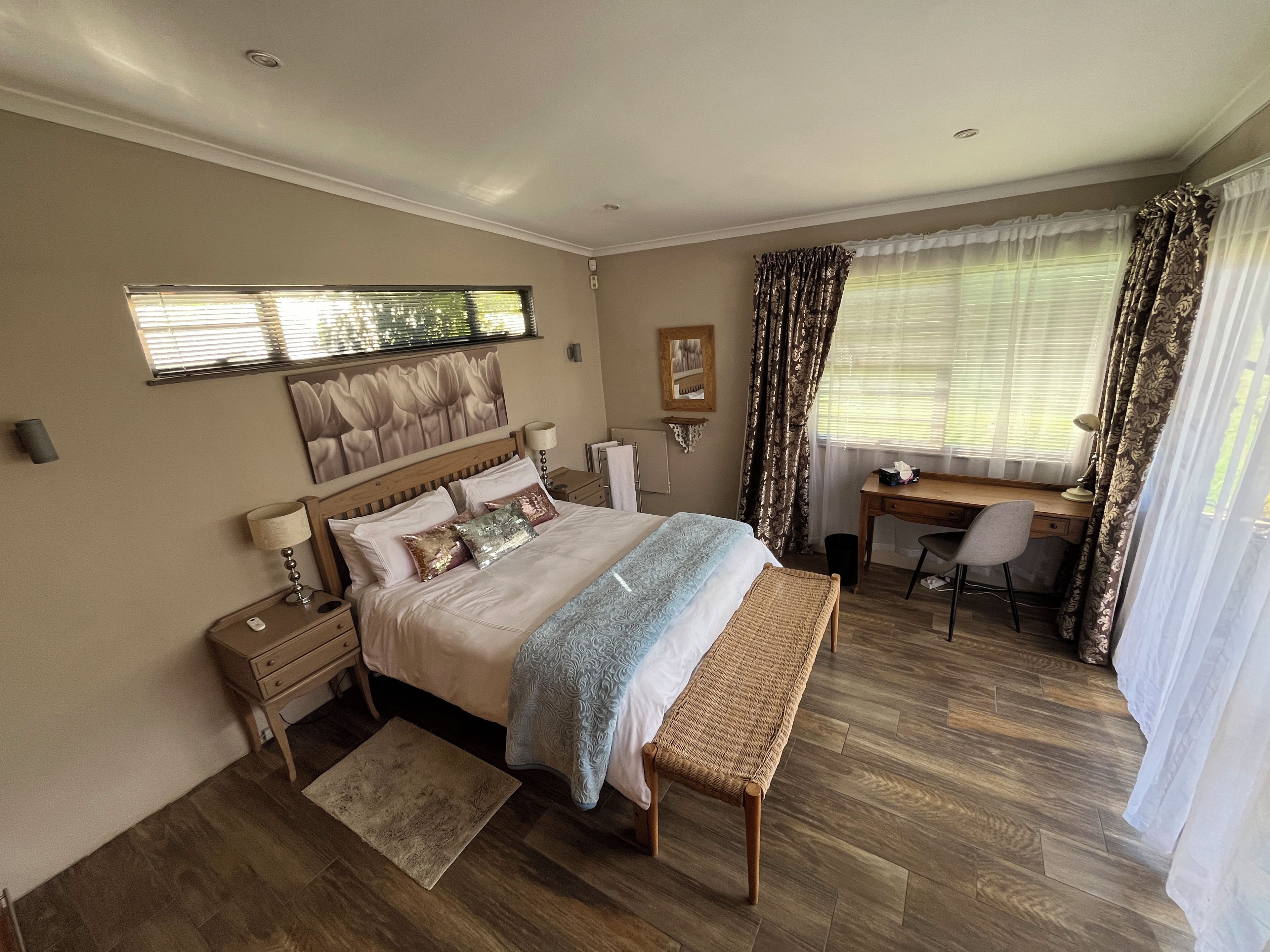 A bedroom with a bed, bedside tables, a desk, a chair, and a window with curtains.