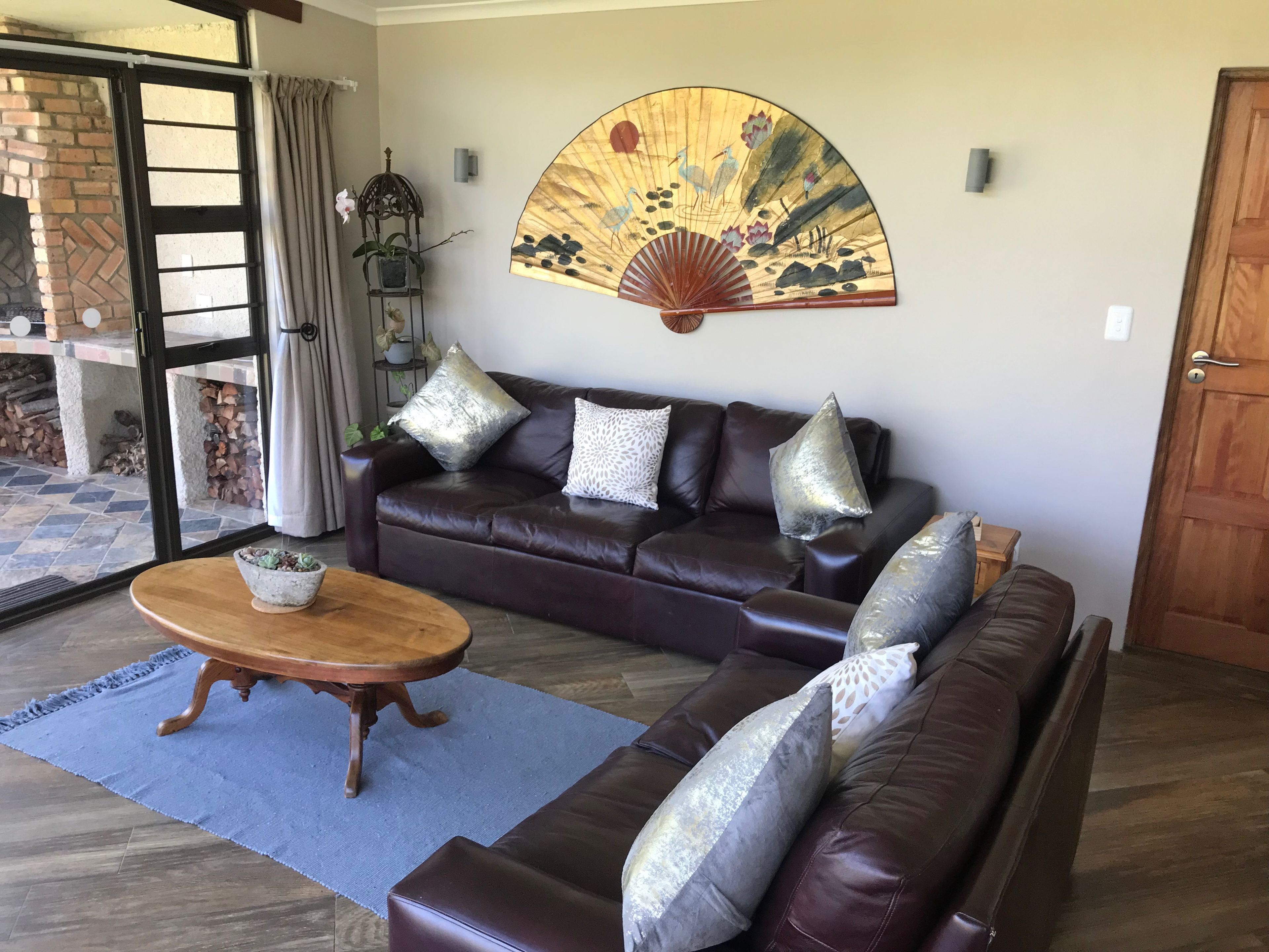 A living room with a brown leather sofa, a wooden coffee table, and a decorative fan on the wall.