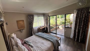 Una camera da letto con un letto grande, una scrivania e vista su un giardino tramite una porta scorrevole.