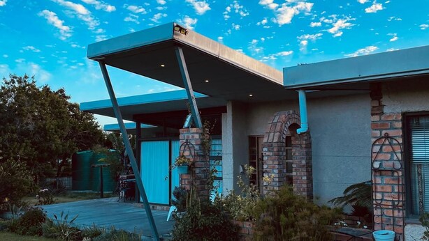 A modern house with a covered patio, brickwork, and a well-maintained garden. - The Stables (Gqeberha)