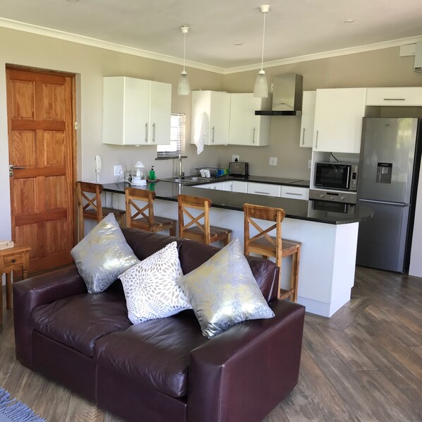 A modern kitchen with white cabinets, a stainless steel refrigerator, and a built-in microwave.