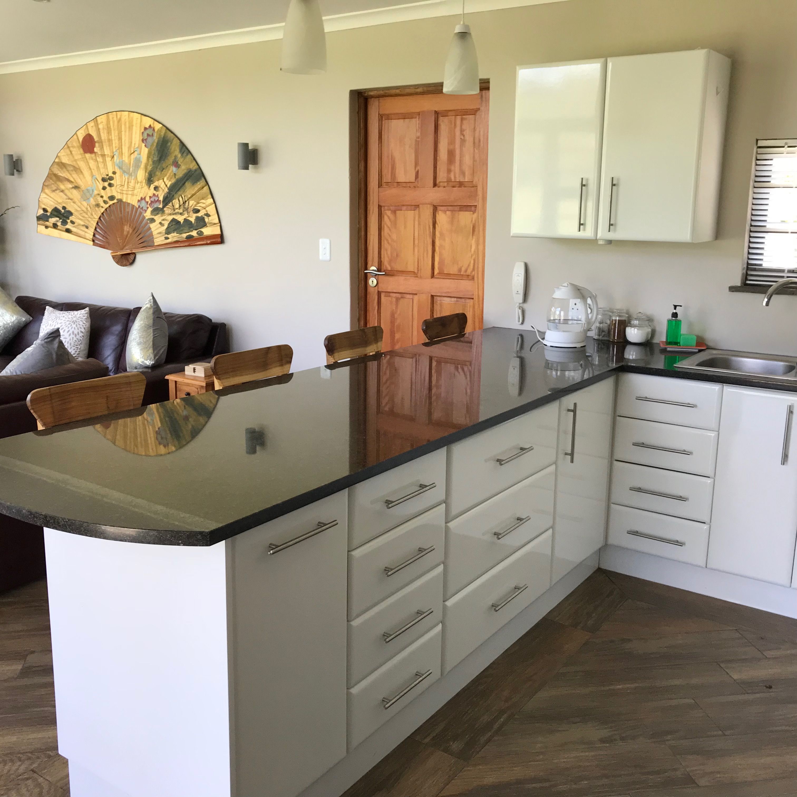 Una cocina con una isla central, armarios blancos y una puerta de madera.