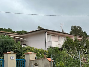 A residential building with a beige facade, a red-tiled roof, and a blue gate. - Apartment 'Bilocale Dolores' with Shared Pool, Wi-Fi and Air Conditioning (Campo nell'Elba)