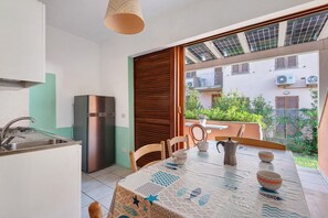 Eine kleine Küche mit Kühlschrank, Spüle und Esstisch, gedeckt mit Kaffeekanne und Tassen.