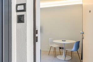 A room with a white door, a white table with two chairs, and a small blue object on the table. - Apartment 'Calcagno Home 3' with Private Terrace, Wi-Fi and Air Conditioning (Milazzo)