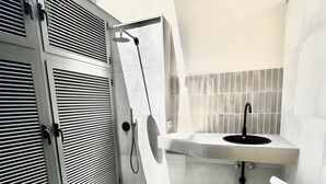 Un bany modern amb dutxa, rentapel i parets de rajola blanca.