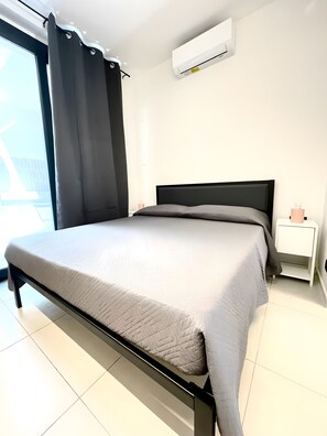 Et moderne soveværelse med seng, natbord, klimaanlæg og udsigt ud