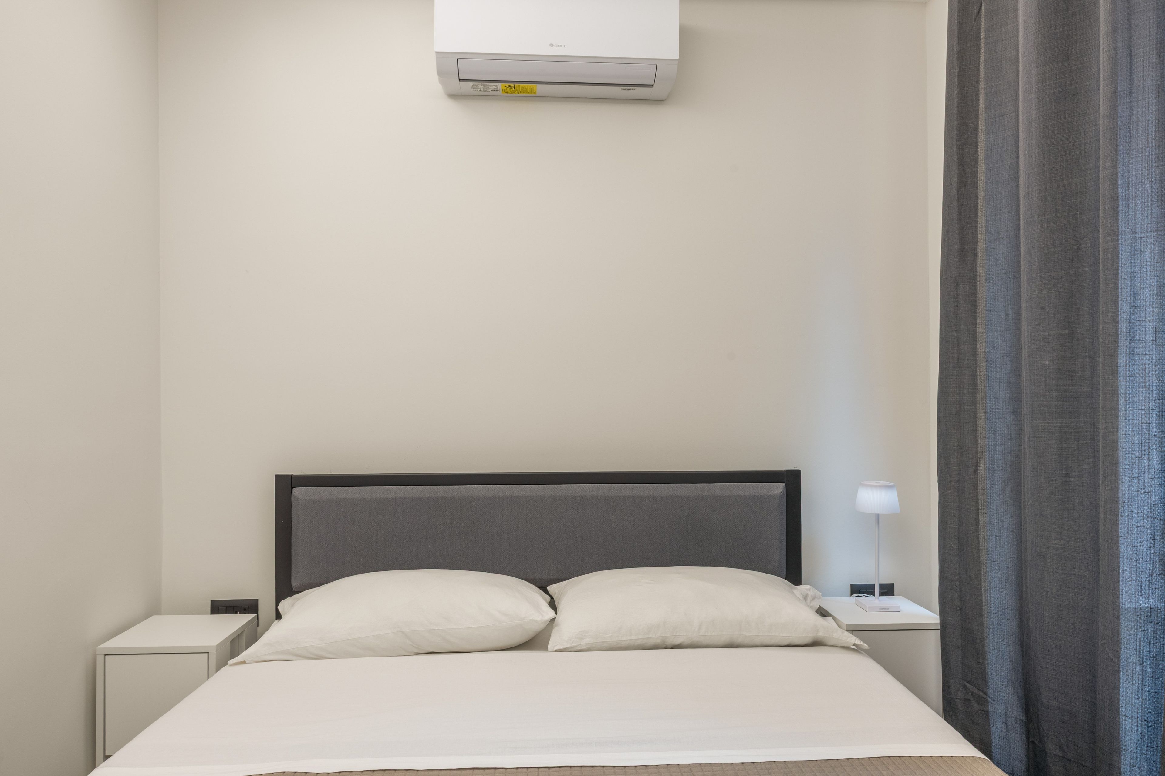 Ein Hotelzimmer mit einem Bett, zwei Nachttischen, einer Klimaanlage und einer Lampe.