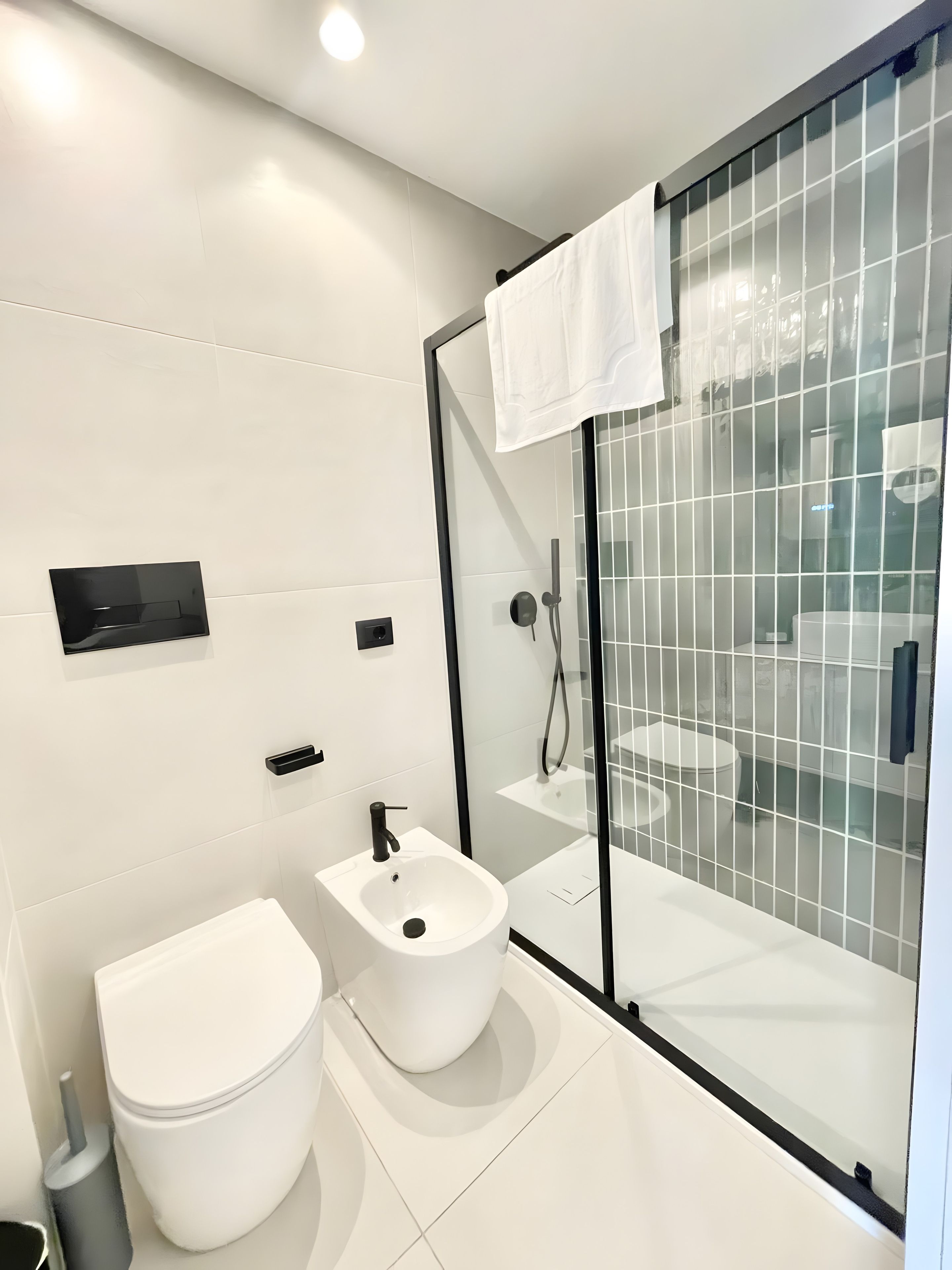 A modern bathroom with a glass shower enclosure, a white toilet, and a bidet.