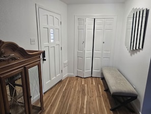 A hallway with wooden flooring, white double doors, a bench, and a wall-mounted radiator. - Amazing 3-bedroom house with AC in enchanting Midland (Midland)