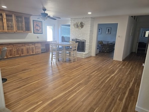 A spacious living area with a dining table and chairs, a stone fireplace, and wooden flooring. - Amazing 3-bedroom house with AC in enchanting Midland (Midland)