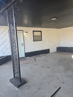 A room with a white textured wall, a door, a window, and a decorative metal railing. - Amazing 3-bedroom house with AC in enchanting Midland (Midland)