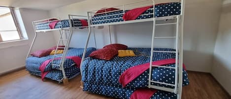 A room with three bunk beds, each with a ladder, and a window providing natural light.