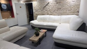 A modern living room with a white leather sofa, a wooden coffee table with a plant, and a stone wall.