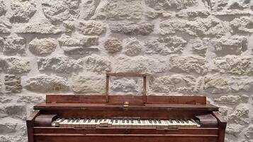 Un piano en bois adossé à un mur de pierre à la texture marquée.