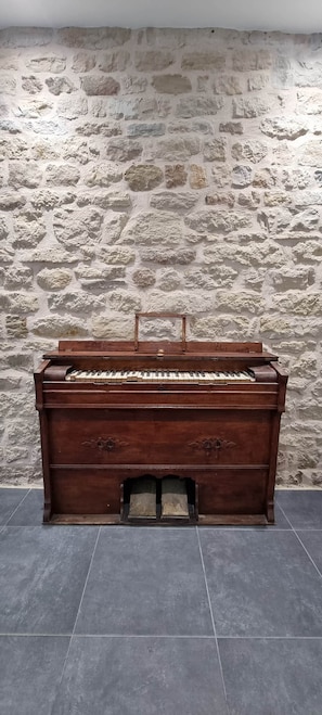 Un piano en bois adossé à un mur de pierre à la texture marquée.