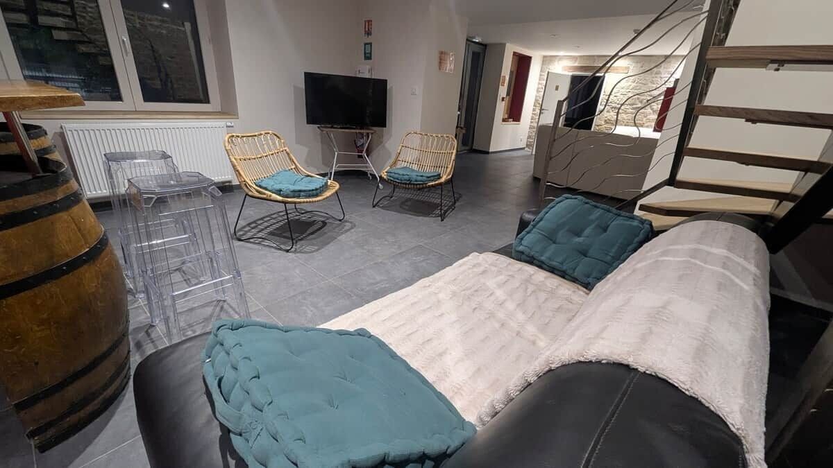 A modern living room with a sofa, two chairs, a television, and a wooden barrel.