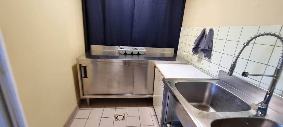 Een kleine keuken met een roestvrijstalen spoelbak, een inbouwoven en een klein aanrecht.