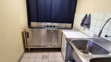Een kleine keuken met een roestvrijstalen spoelbak, een inbouwoven en een klein aanrecht.
