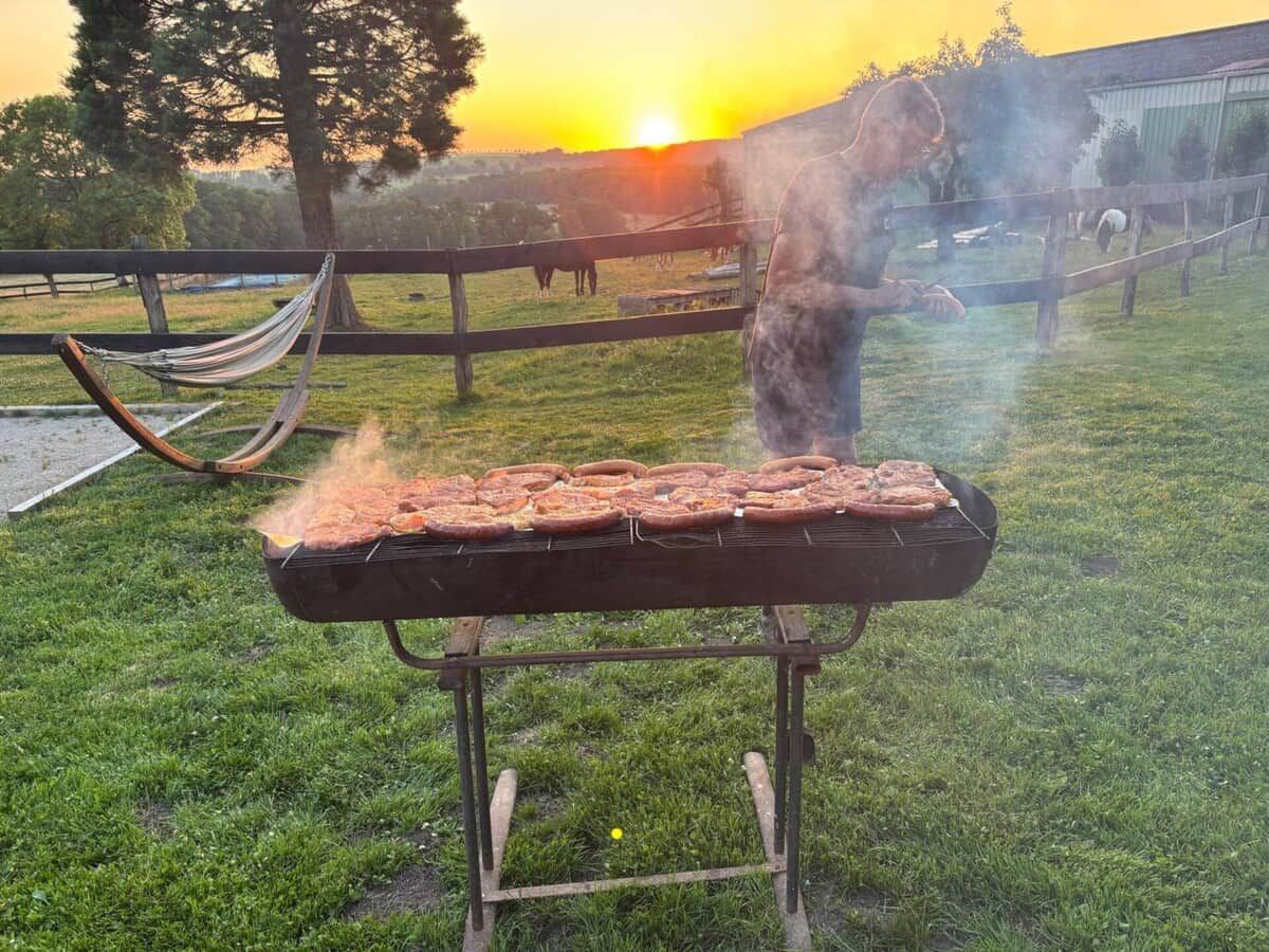 En grill utomhus med en solnedgång i bakgrunden.