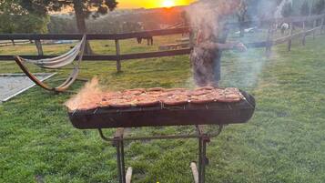 En grill utomhus med en solnedgång i bakgrunden.