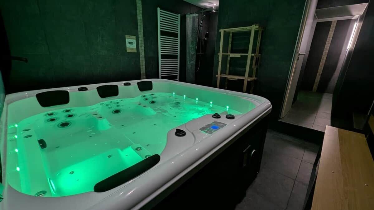 A spa room with a large hot tub, a wooden ladder, and a tiled floor.