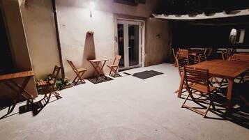 Un espace patio extérieur avec une table et des chaises, une porte et un luminaire fixé au mur.
