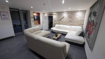Un salon moderne comprenant un ensemble de canapés, une table basse et un mur décoratif en pierre.