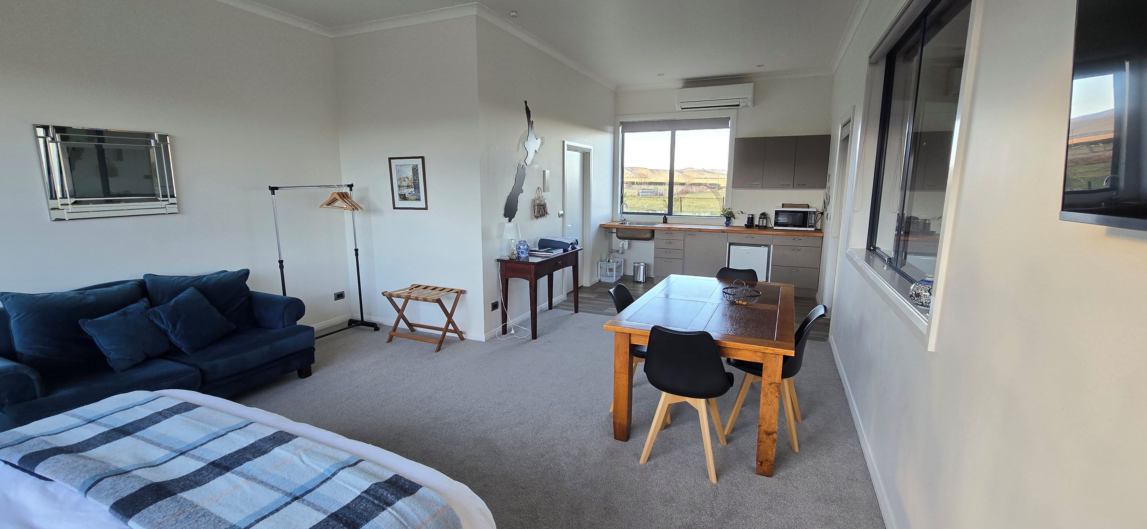 Un espacio habitable compacto con sofá, mesa de comedor con sillas, una pequeña cocina y ventana con vistas.