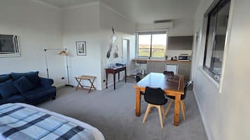 Un espacio habitable compacto con sofá, mesa de comedor con sillas, una pequeña cocina y ventana con vistas.