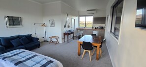 Un espacio habitable compacto con sofá, mesa de comedor con sillas, una pequeña cocina y ventana con vistas.