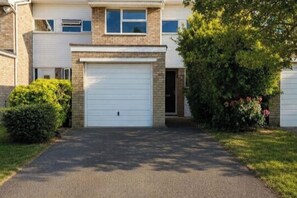 A two-story house with a garage, a driveway, and a well-maintained lawn. - Bright 2BDR Flat with King Bed in West London (Greater London)
