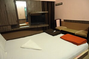 Una habitación de hotel con una cama, un televisor, una mesita y un banco.
