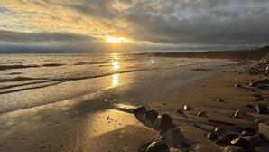 Uma praia com rochas e um pôr do sol.