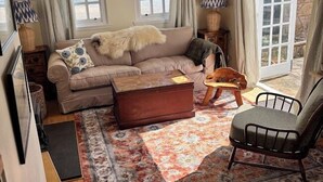 Sala de estar com sofá, mesa de centro, poltrona e vista para o exterior.