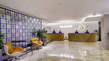 A hotel reception area with a modern design, featuring a reception desk, seating area, and decorative elements.