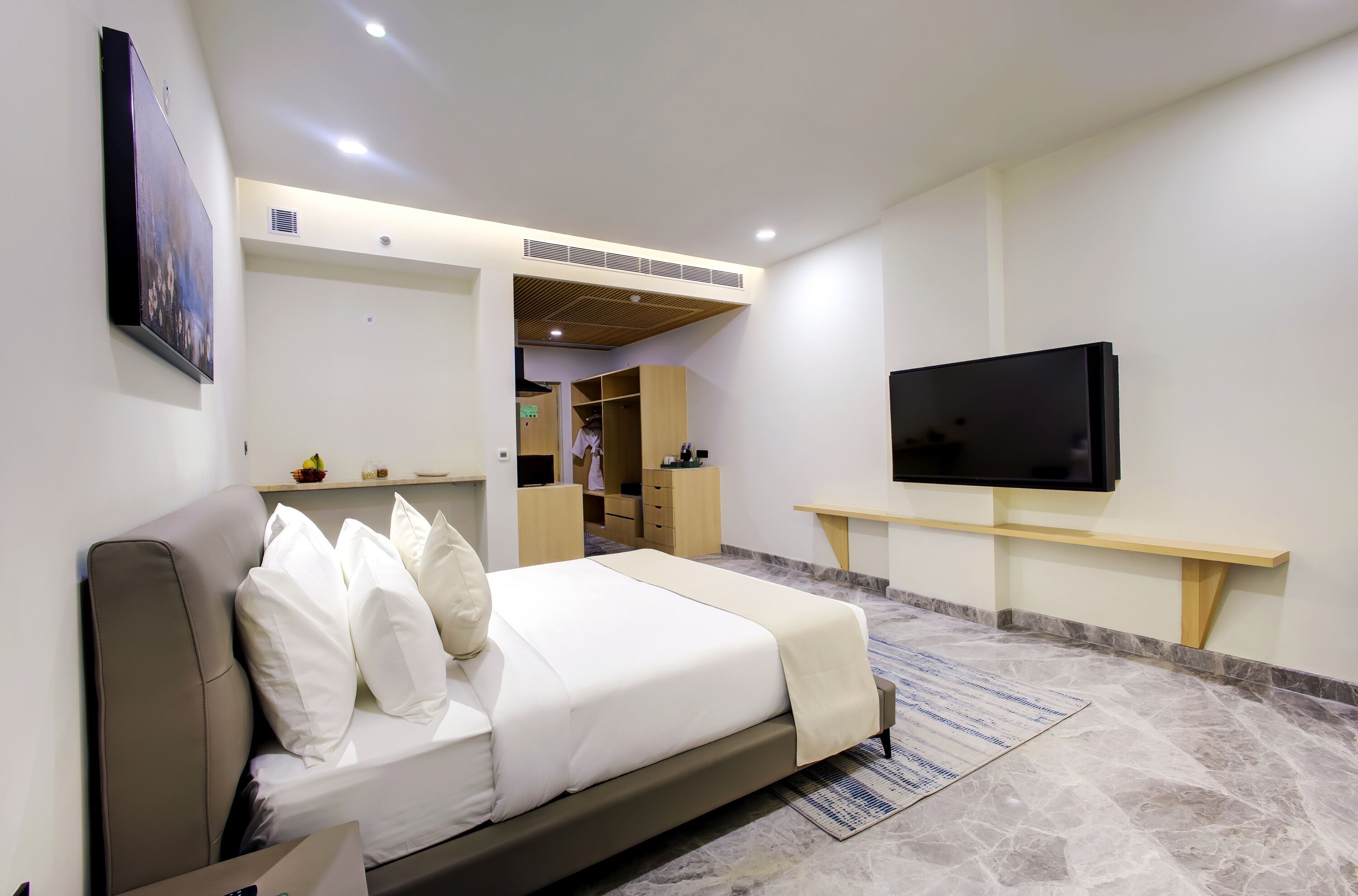 Un dormitorio moderno con cama, televisor y armario.