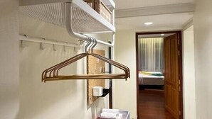 A hotel room with a white wall-mounted rack, a wooden door, and a visible bed in the background. - Nueng Rana 149 | A Unique Stay Experience | BKK - Holiday Home (Samphanthawong)