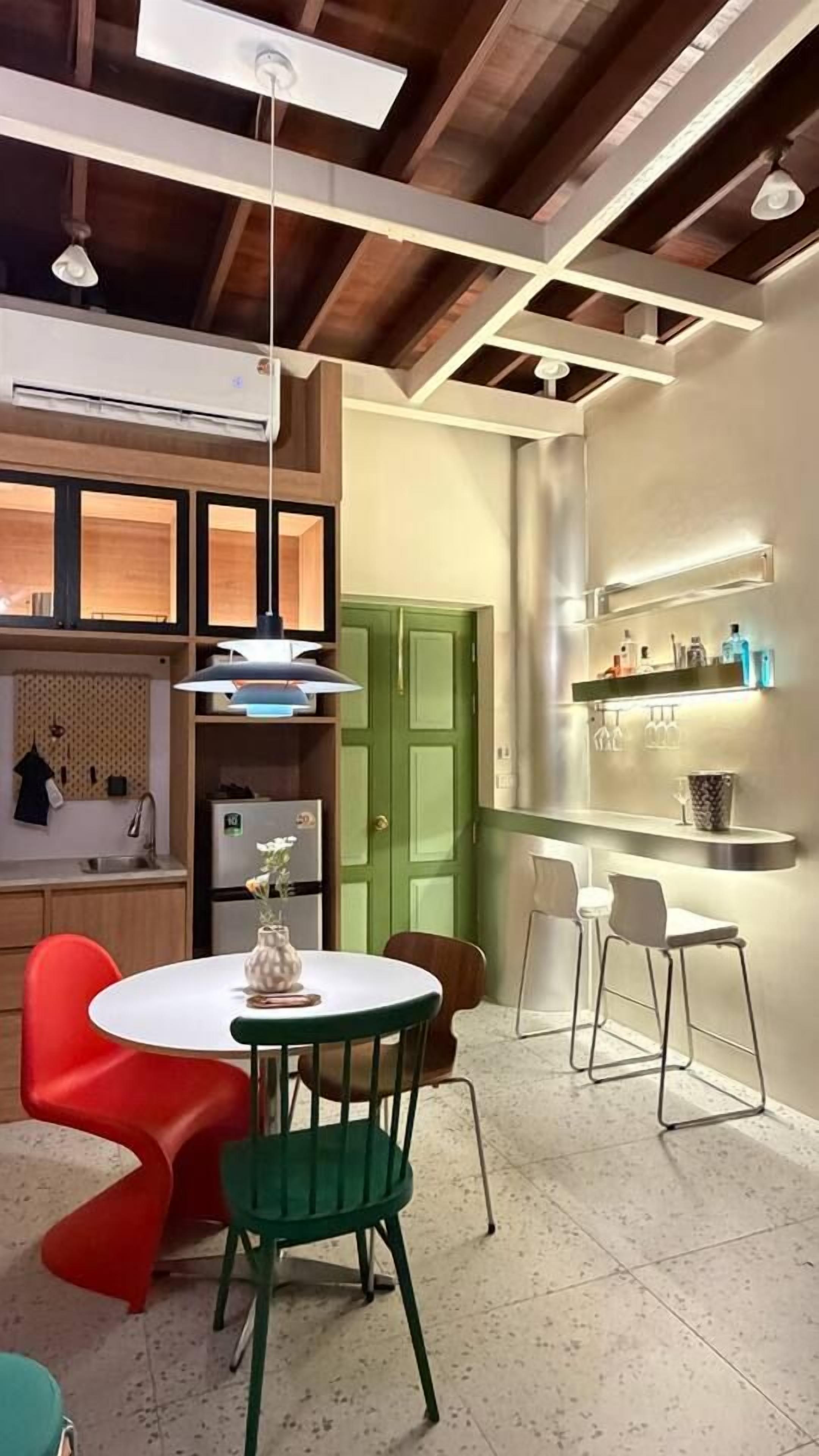 A modern kitchen with a dining area, featuring a round table, chairs, and a green door.