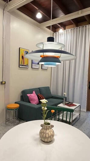 Una sala de estar moderna con un sofá verde, una mesa redonda con un florero y una lámpara colgante.