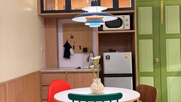 A compact kitchen with a dining area, a green door, and a ceiling fan. - Nueng Rana 149 | A Unique Stay Experience | BKK - Holiday Home (Samphanthawong)