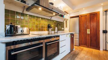 A modern kitchen with stainless steel appliances, a marble countertop, and a green-tiled backsplash.
