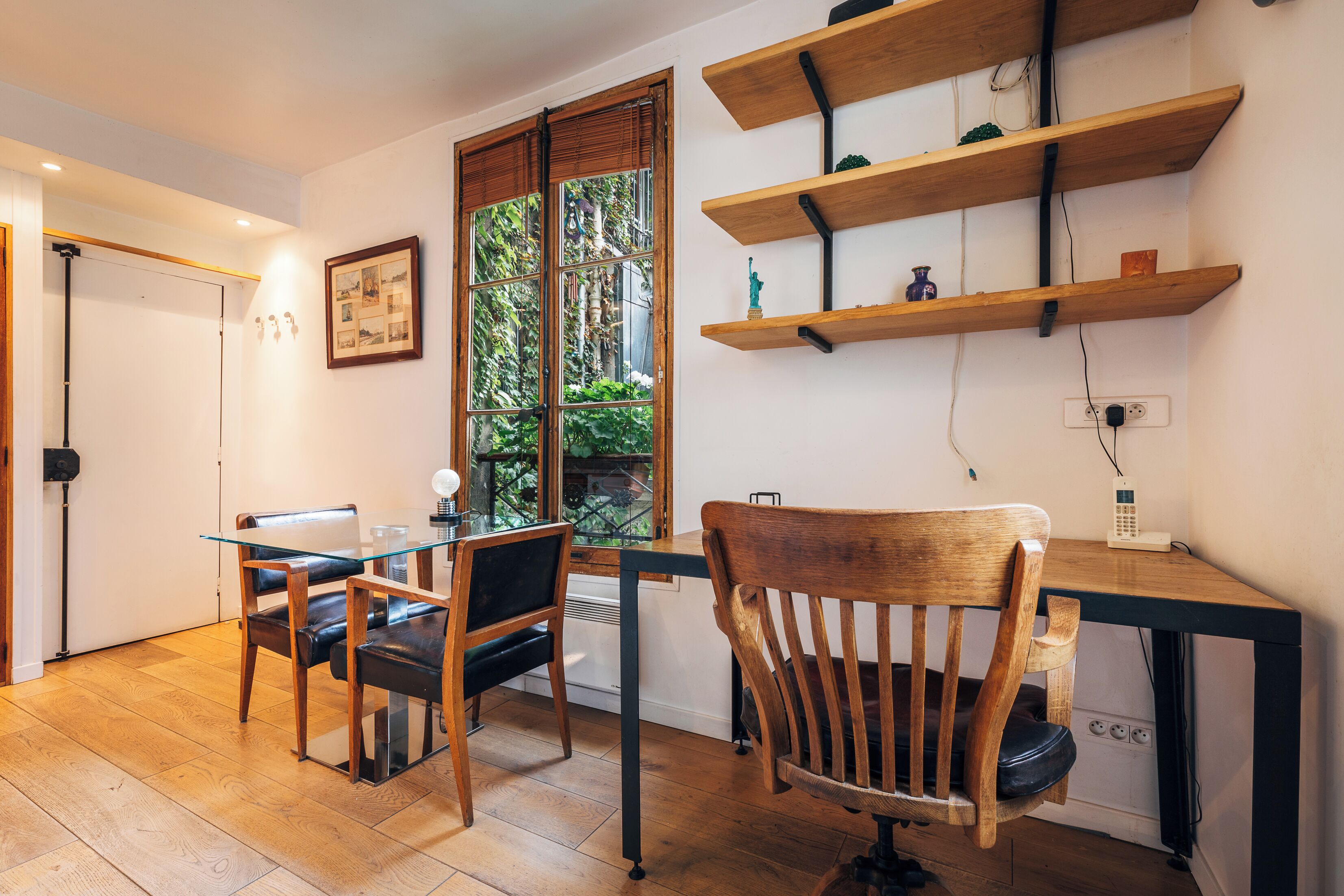 A modern kitchen with wooden flooring, a glass dining table, and a wooden chair.