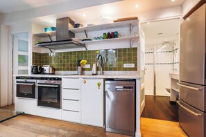 A modern kitchen with built-in appliances, a dishwasher, and a glass shower enclosure.