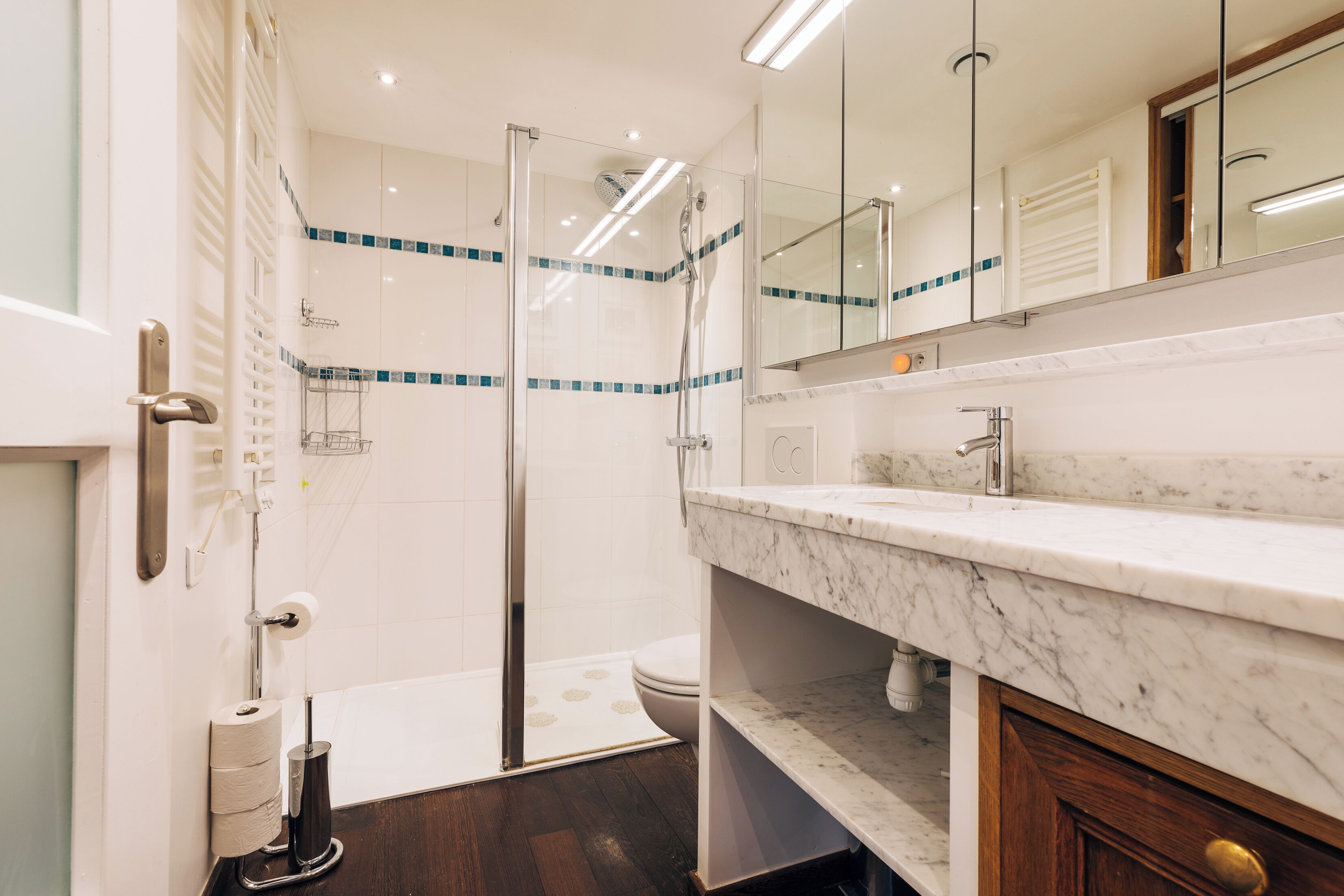 Une salle de bain moderne avec une douche à parois de verre, un lavabo en marbre et des toilettes.