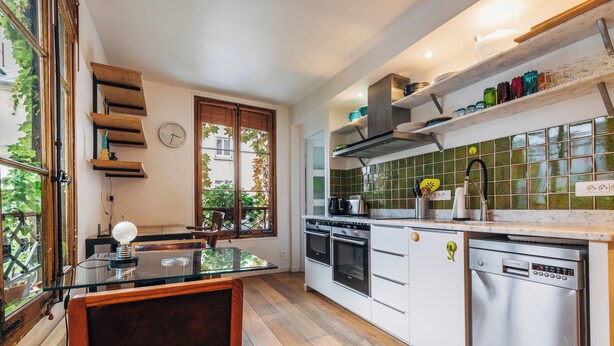 Una cocina moderna con armarios blancos, electrodomésticos de acero inoxidable y una mesa de comedor de vidrio.