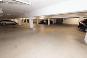 A multi-level parking garage with several cars parked, clear directional arrows on the floor, and visible structural columns. - Ardell - Aceessible Location - Comfortable 1BR - FREE Garage (Vienna)